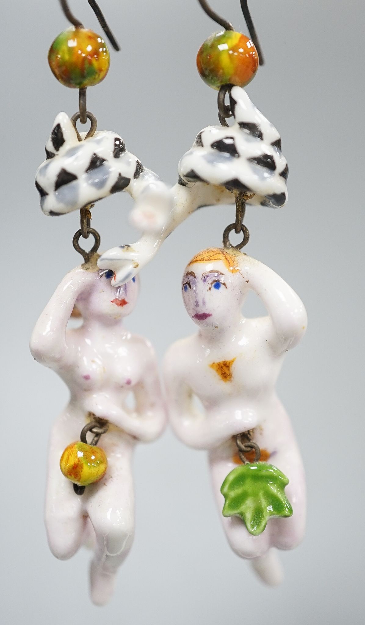 A pair of painted porcelain 'Adam & Eve with serpent' drop earrings, 62mm